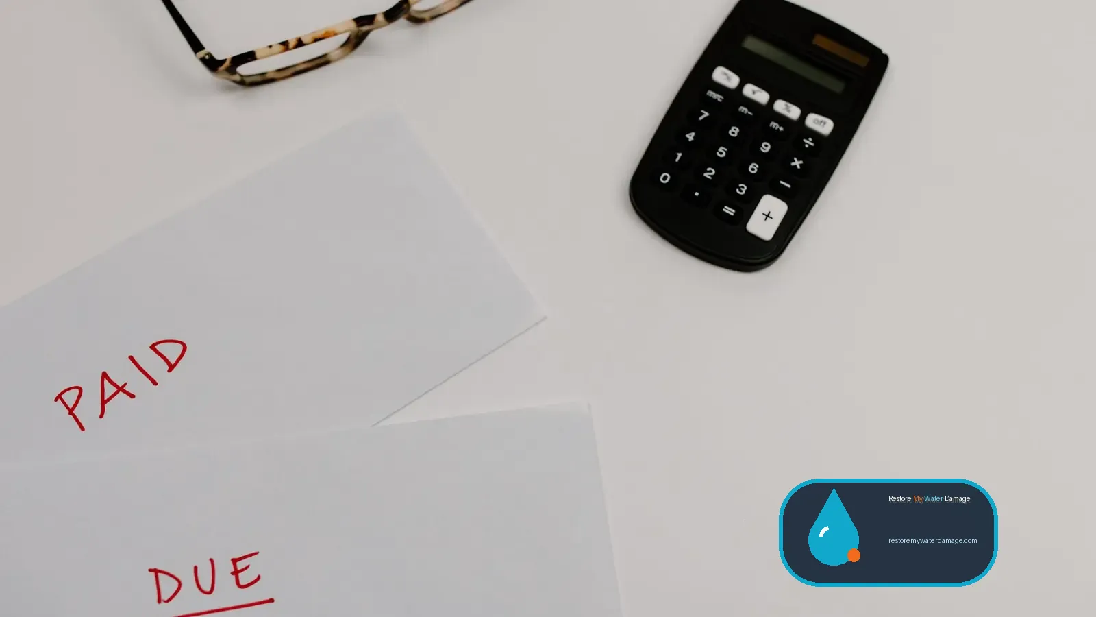 Calculator beside paid and due bills, tallying a water damage restoration cost breakdown