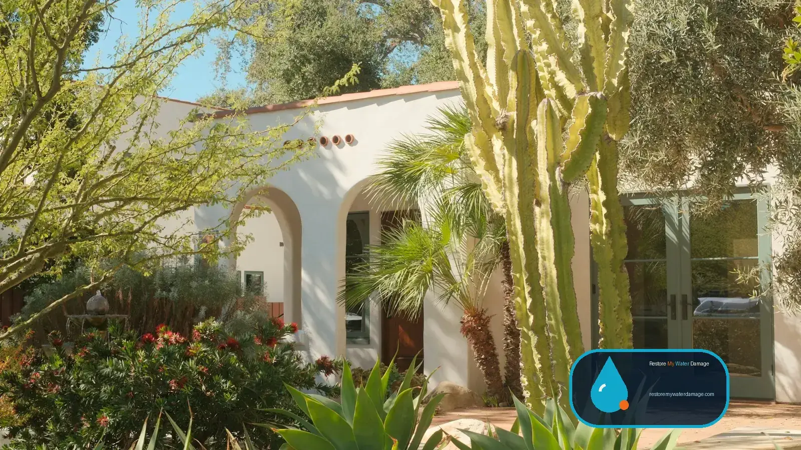 Stucco house framed by cactus and succulents in a dry garden, setting for water damage restoration Henderson, NV