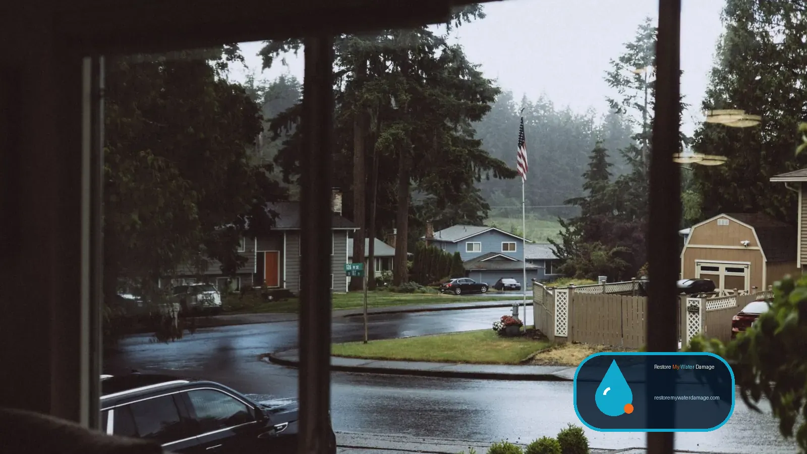 Rainy suburban street seen through a window, before water damage restoration in North Carolina